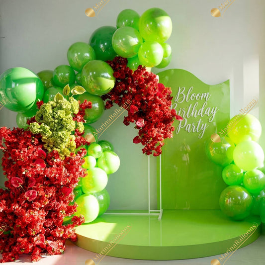 A vibrant green-and-red floral balloon setup with lush blooms and glossy balloons - a bold, garden-inspired backdrop for a bright and unforgettable birthday celebration.