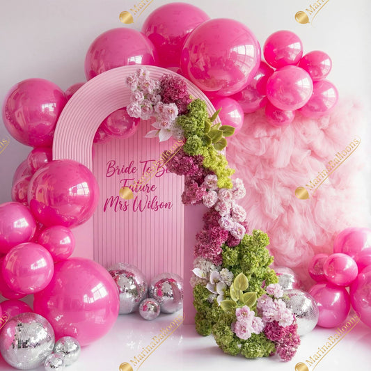 A glamorous bridal setup in bright pink tones with glossy balloons, lush florals, and sparkling disco balls - the perfect photo zone for a bride-to-be celebration.