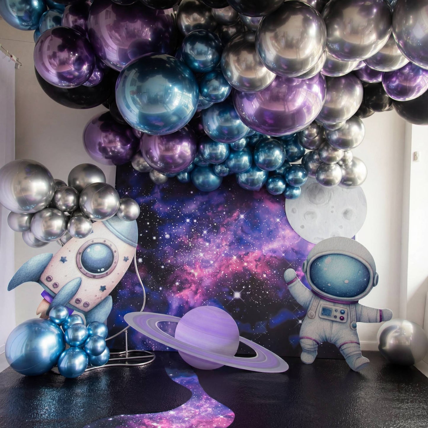 A vibrant space-themed setup with metallic balloons, a galaxy backdrop, planets, a rocket, and a cute astronaut - the perfect photo zone for a space-loving kids birthday.