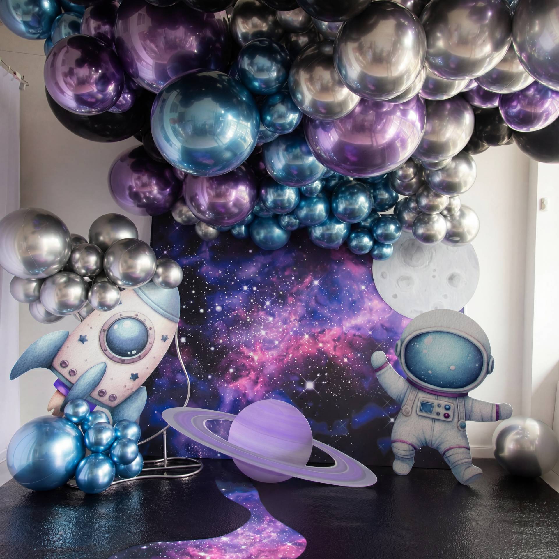 A vibrant space-themed setup with metallic balloons, a galaxy backdrop, planets, a rocket, and a cute astronaut - the perfect photo zone for a space-loving kids birthday.