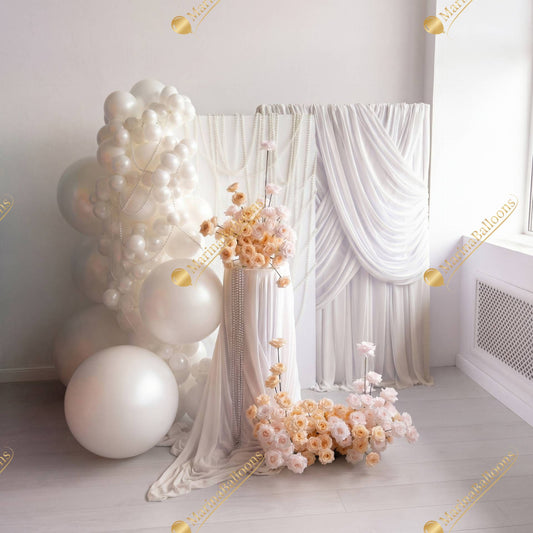 A sophisticated all-white setup with draped fabric, pearl details, and romantic florals - a timeless and luxurious backdrop for weddings or bridal events.