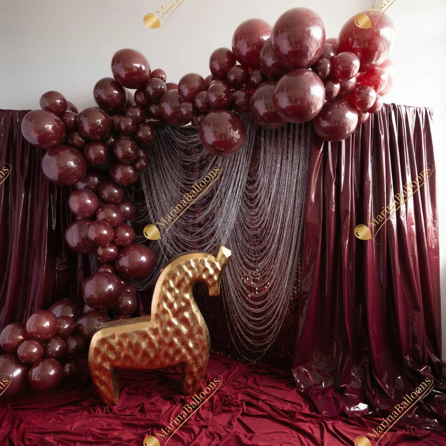 A deep burgundy luxury setup with glossy balloons, shimmering draped textures, and a sculptural golden horse - a dramatic, high-end photo zone for parties, fashion events, and premium celebrations.