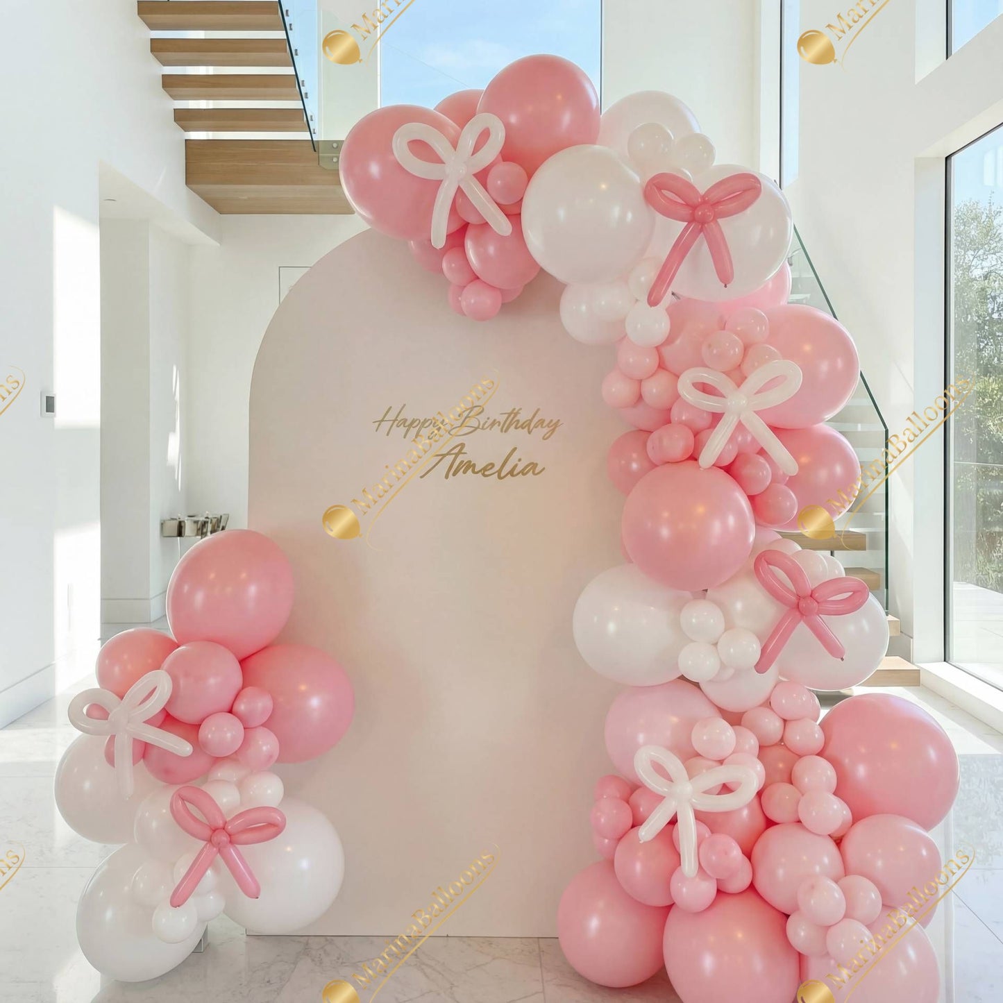 A soft pink-and-white backdrop with bow details - a sweet and modern setup for a stylish birthday celebration.