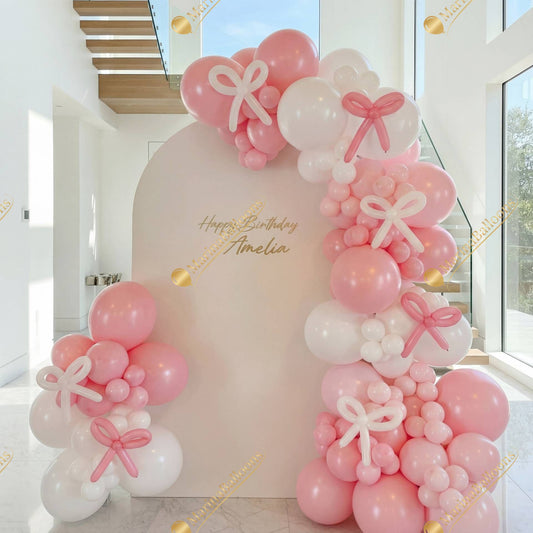 A soft pink-and-white backdrop with bow details - a sweet and modern setup for a stylish birthday celebration.