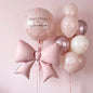 Pink birthday balloon bouquet with a large pink foil bow, a clear round balloon reading 'Happy birthday my sweetheart!' with small pink bow details, and a cluster of blush, cream, and rose-gold balloons against a soft pink background.